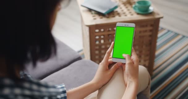 家でデバイスを使用して現代のスマートフォンの緑のモックアップ画面をタッチする女の子 — ストック動画