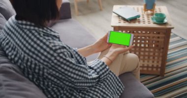 Evde kanepede oturan Smartphone yeşil mock-up ekrana bakarak kız