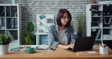 Ofis içinde laptop ile çalışan kadın portre daha sonra kamera gülümseyen bakıyor