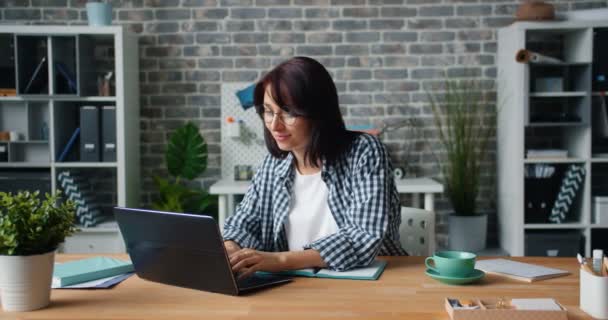 Movimento lento de mulher atraente trabalhando com laptop na mesa no escritório sozinho — Vídeo de Stock