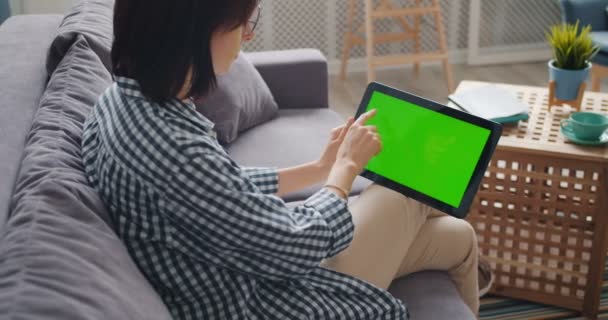Giovane signora toccare schermo verde del tablet moderno utilizzando gadget in appartamento — Video Stock