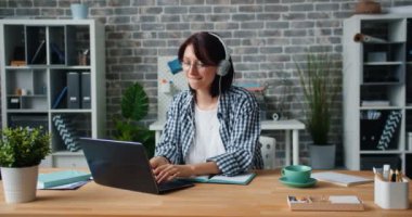 Genç Bayan içinde kulaklık zevk müzik çalışma ile laptop içinde ofis iş