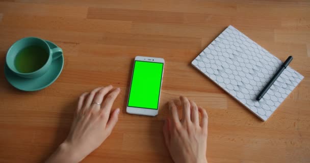 Movimento lento delle mani delle donne che si muovono sul tavolo con lo smartphone schermo verde — Video Stock