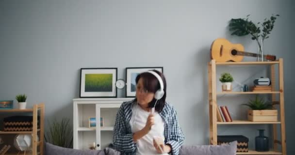 Powolny ruch radosnej kobiety słuchanie muzyki taniec zabawy w mieszkaniu — Wideo stockowe