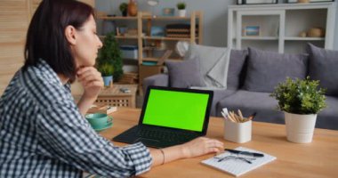 Evde medya izlerken yeşil mock-up laptop ekran bakarak genç kadın