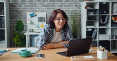 Güzel kız iş yerinde dizüstü ekran işaret bakıyor konuşurken ofiste Skyping
