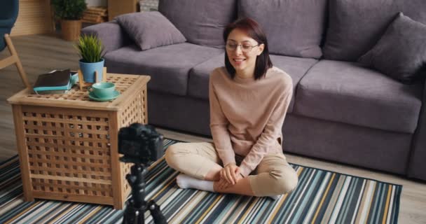 Blogger femenina grabando vídeo en casa hablando y haciendo gestos con cámara — Vídeo de stock