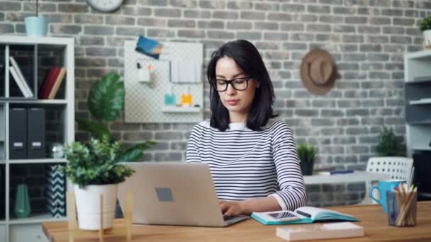 Kameraya bakarak gülümseyen dizüstü bilgisayar ile çalışan güzel busineswoman Portresi — Stok video