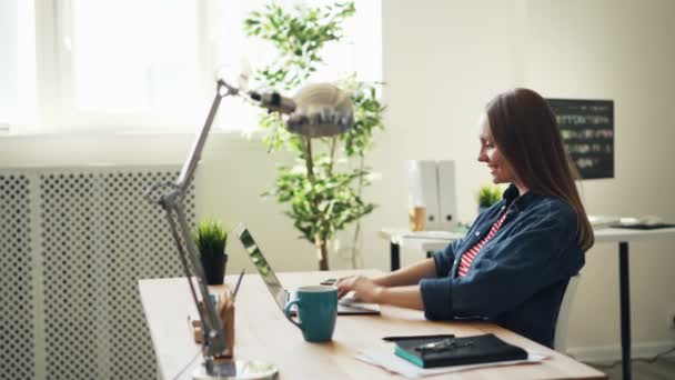 Tillbaka syn på vacker kvinna med hjälp av laptop i Office sedan vilar leende — Stockvideo