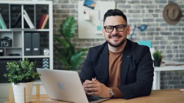 Zoom-in portrait of attractive guy using laptop then looking at camera smiling — 비디오