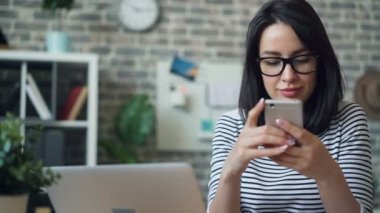 İşyerinde gülümseyen akıllı telefon ekranına dokunan çekici genç bayan