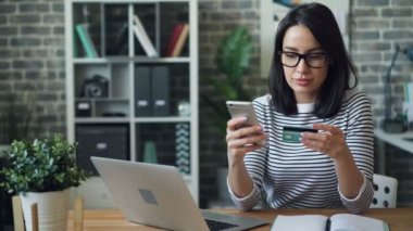 İş yerinde akıllı telefon kullanarak kredi kartı ile ödeme yapan genç kadının portresi