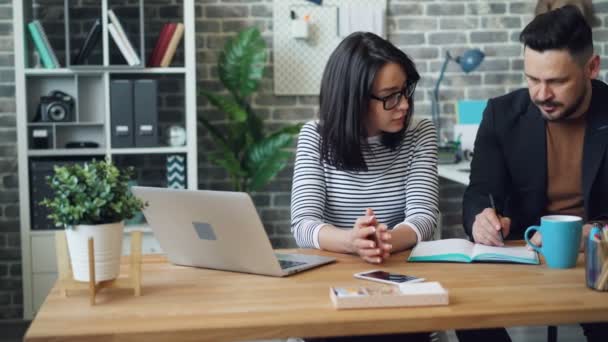 Mädchen und Mann diskutieren Geschäftsideen Strategie Schreiben in Notizbuch im Büro — Stockvideo