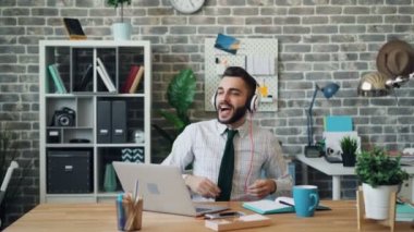 Neşeli adam kulaklık kullanarak iş yerinde dans müzik şarkı dinlerken
