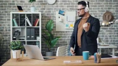 Neşeli girişimci kulaklık takarak müzik dansı dinlerken eğleniyor