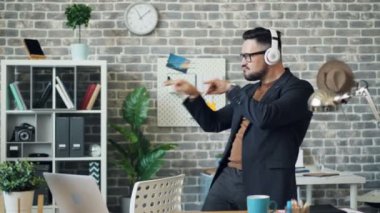 Kulaklıklı adam ofiste dans ederken iş molasının keyfini çıkaran müzik dinliyor