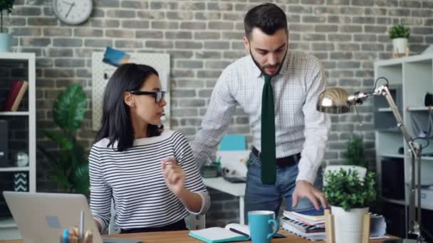 Hombre y mujer colegas leyendo documento y luego mirando a la pantalla del ordenador portátil — Vídeos de Stock