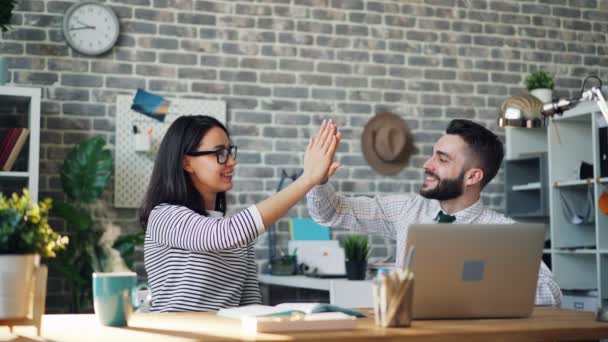 Cinemagraph de colegas felizes fazendo high-five no escritório na mesa com laptop — Vídeo de Stock