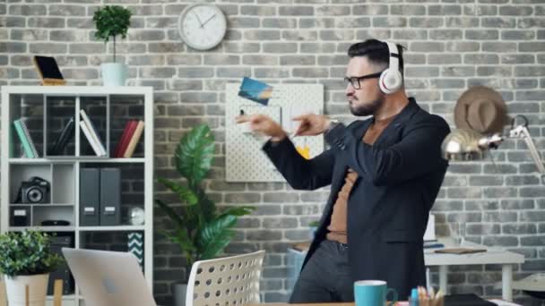 Man in headphones dancing in office listening to music enjoying work break — Stock Video