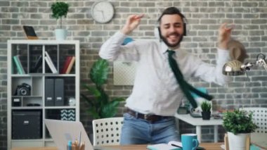 Neşeli ofis çalışanı işyerinde dans kulaklık müzik dinlerken