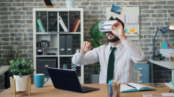 Joven usando gafas de realidad virtual en el trabajo usando un gesto de auriculares — Vídeos de Stock