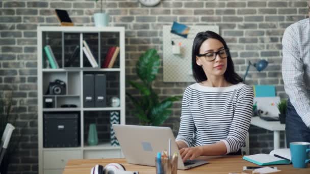 Привлекательная женщина, работающая с ноутбуком, обсуждает работу с коллегой-мужчиной — стоковое видео