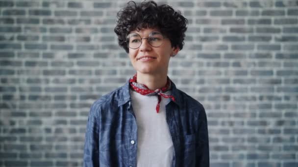 Retrato de una mujer guapa guiñando sonriendo mirando a la cámara sobre un fondo de ladrillo — Vídeos de Stock