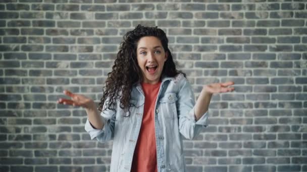 Porträt eines aufgeregten Mädchens, das sich nach guter Überraschung auf Ziegelgrund glücklich fühlt — Stockvideo