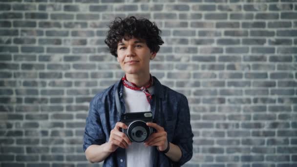 Retrato de fotógrafa tomando fotos con cámara sobre fondo de ladrillo — Vídeos de Stock