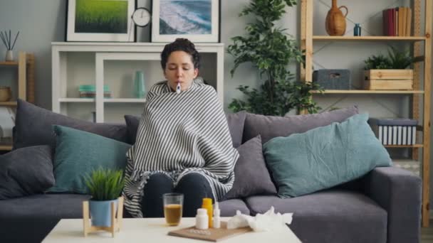 Schüttelfrost Studentin nimmt Körpertemperatur sitzend mit Thermometer im Mund — Stockvideo