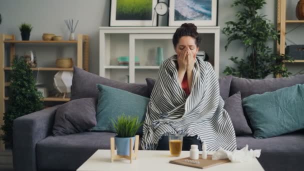 Zieke jonge vrouw hoesten drinken geneeskunde zittend op de Bank thuis — Stockvideo