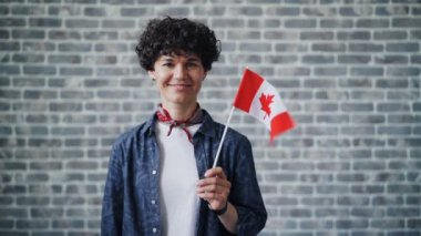 Tuğla arka plan üzerinde Kanada bayrağı tutan sevimli öğrencinin yavaş hareket portresi