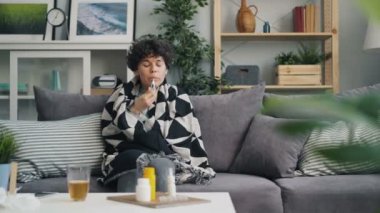 Termometre ile mutsuz genç kadın sıcaklık kontrol sonra kanepede uyuklama