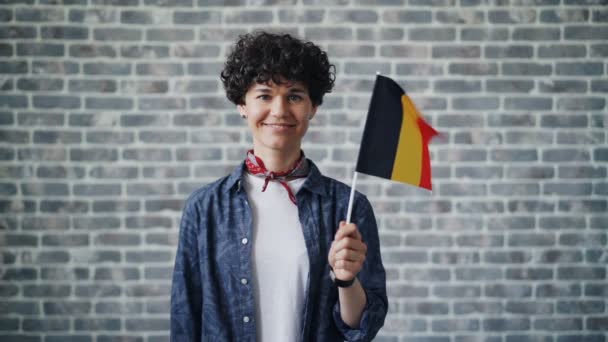 Retrato en cámara lenta de una hermosa mujer sosteniendo la bandera oficial alemana sonriendo — Vídeos de Stock