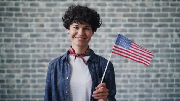 Movimento lento de orgulhoso cidadão americano segurando bandeira sorrindo em fundo de tijolo — Vídeo de Stock