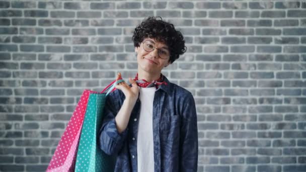 Portrait de jeune femme heureuse tenant des sacs à provisions en papier regardant la caméra — Video