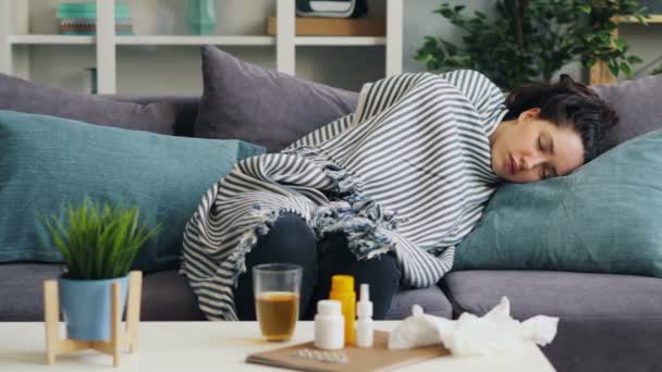 Больной молодой леди дремлет дома на диване под теплым одеялом, расслабляясь. — стоковое видео