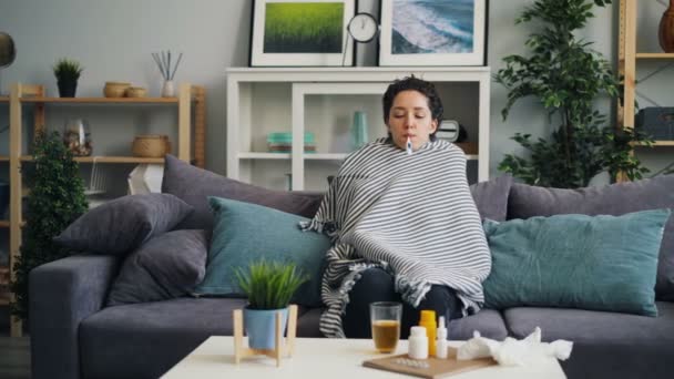 Ill pessoa bonita mulher verificando a temperatura do corpo, em seguida, dormir no sofá em casa — Vídeo de Stock
