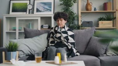 Evde kanepede oturan termometre ile vücut ısısı alarak mutsuz kız