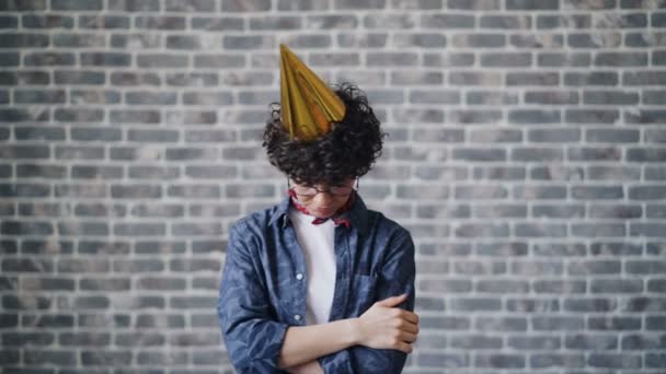 Portret nieszczęśliwy urodziny dziewczyna w imprezie kapelusz stojący skrzyżowane ramiona smutna twarz — Wideo stockowe