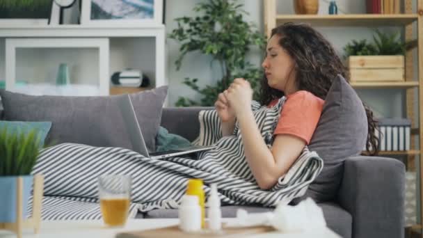 Ung dam lider av hosta och rinnande näsa med laptop hemma — Stockvideo