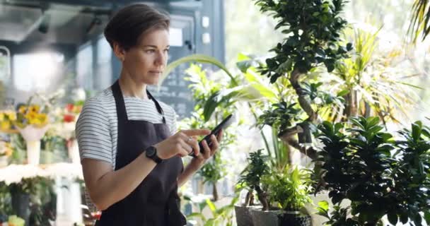 Cámara lenta de la floristería usando tableta en el trabajo contando plantas tocando la pantalla — Vídeos de Stock