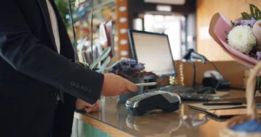 Erkek müşteri akıllı telefon ile ödeme sonra mağazada çiçekçi çiçek alarak