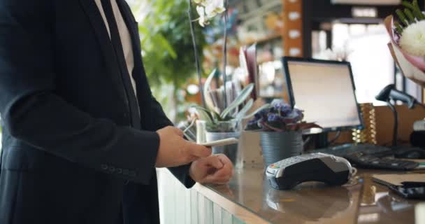 Homme utilisant smartphone pour effectuer le paiement dans la boutique de fleuristes puis prendre bouquet — Video