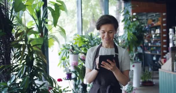Pretty kvinnlig florist Counting växter mata in poster i tablett upptagen med arbete — Stockvideo
