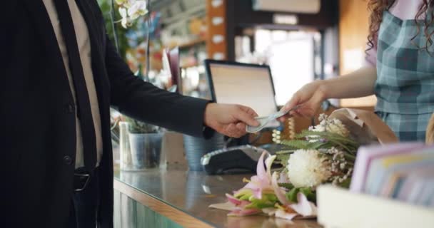 Чоловік купує квіти, платячи готівкою в магазині флористів, даруючи гроші — стокове відео