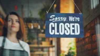 Çekici genç garson kafe kapısında gülümseyerek tabela açmak için kapalı değişen