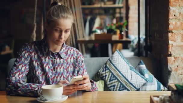 Vonzó fiatal nő a modern okostelefon a kávézóban megható képernyő