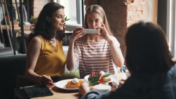 Fiatal nők fotózás étkezés kávézó fényképezés smartphone kamerával — Stock videók