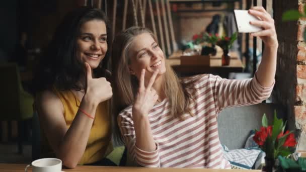 Счастливые молодые женщины делают селфи в кафе показывая большие пальцы вверх и ОК жест — стоковое видео